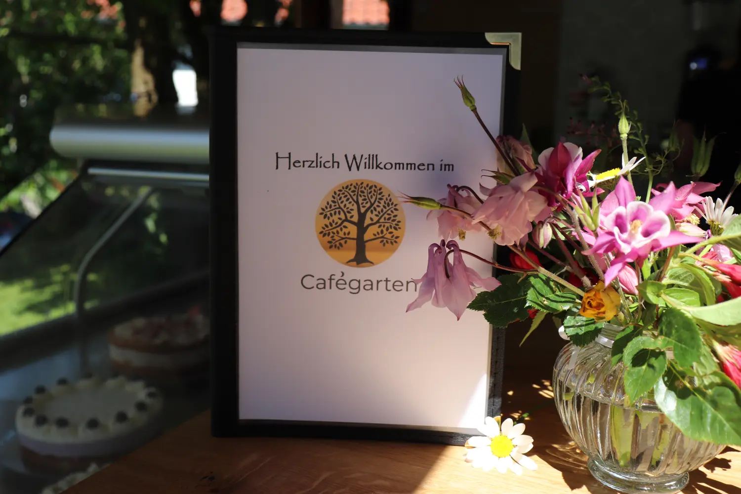 Cafégarten Mondholz - Willkommensschild mit Blumenvase auf Holztisch